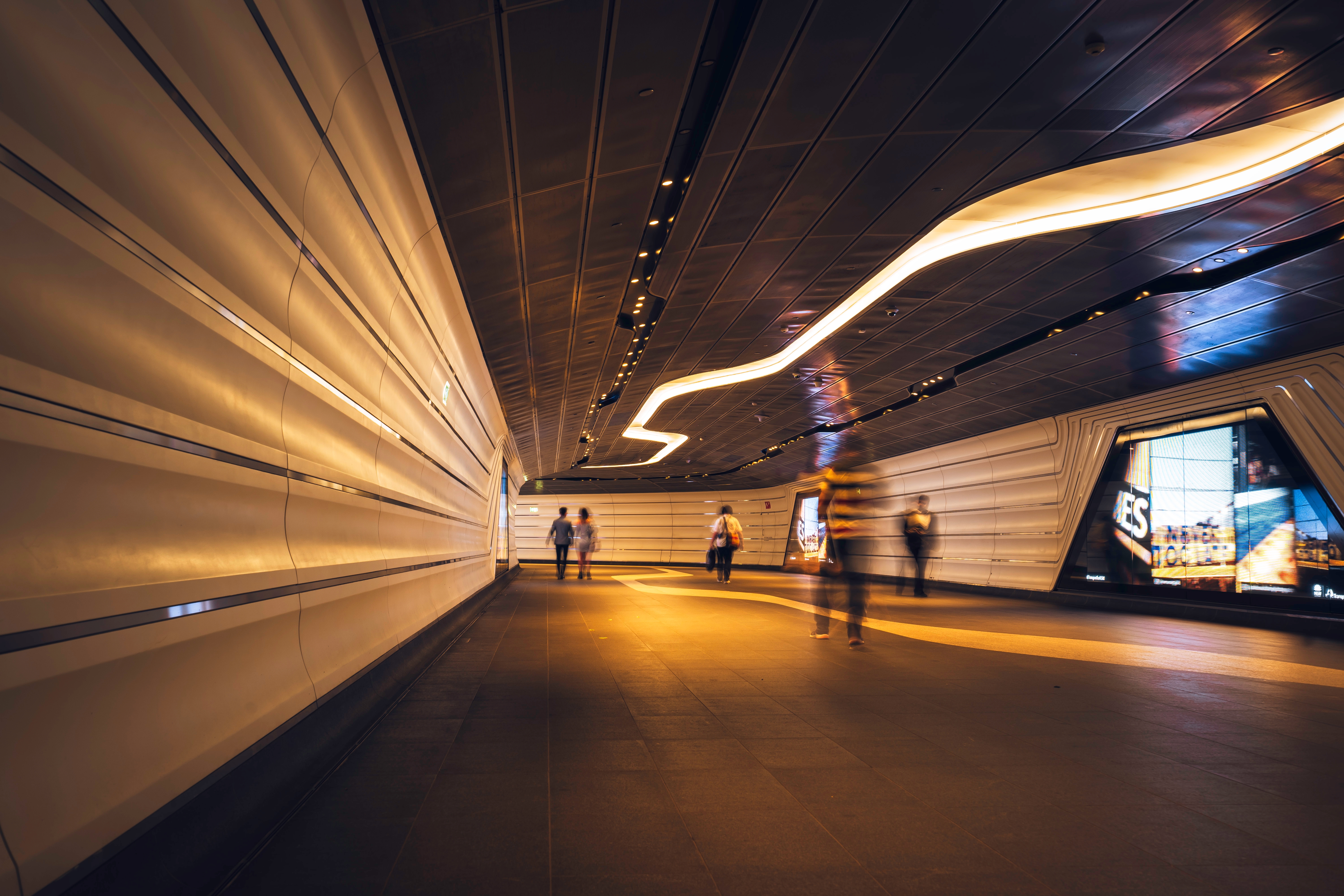 Commuters walking through a futuristic looking pedestrian tunnel featuring an LED integrated lights